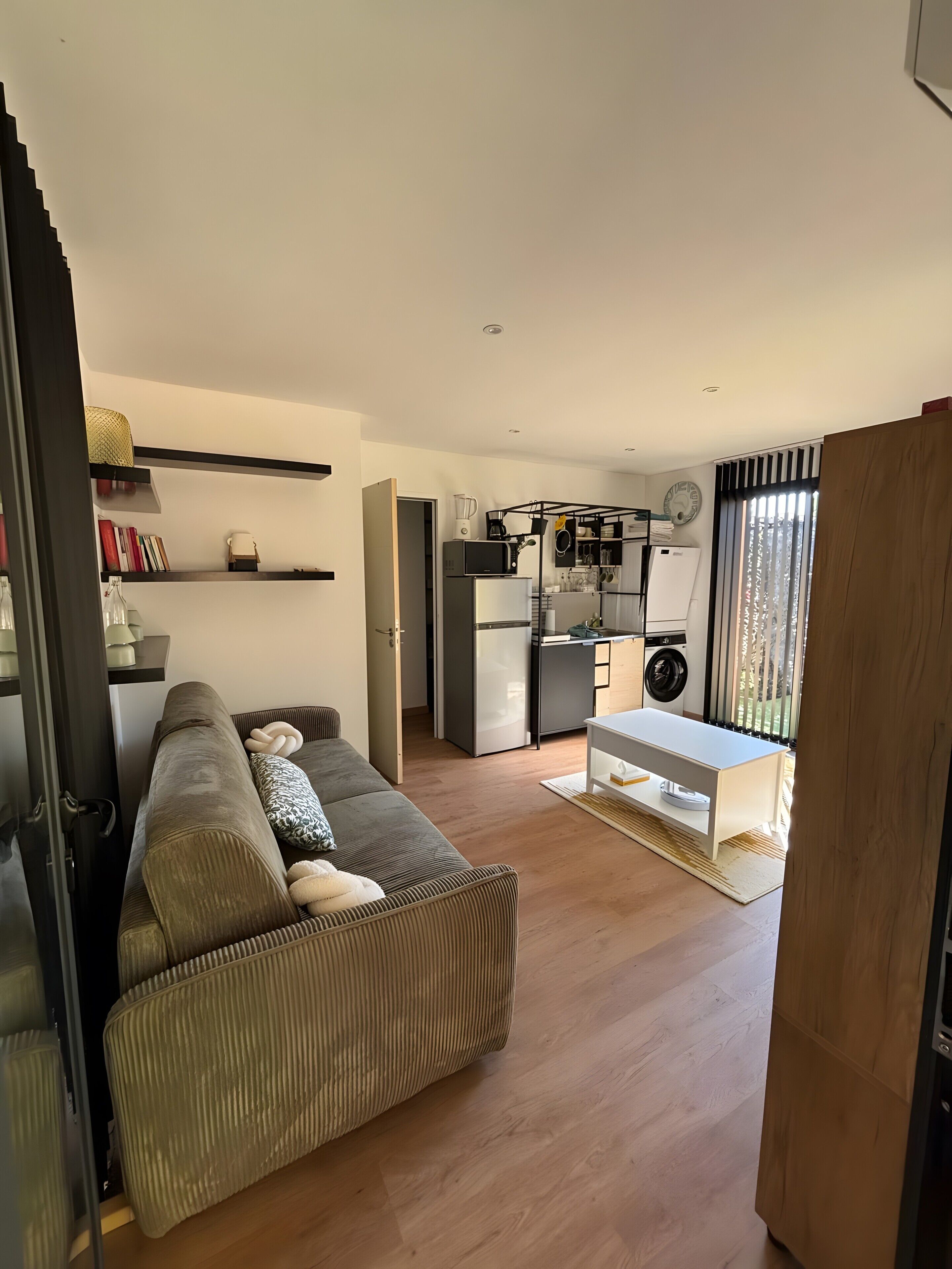 Una sala moderna con sofá, una mesa de comedor y una cocina equipada.