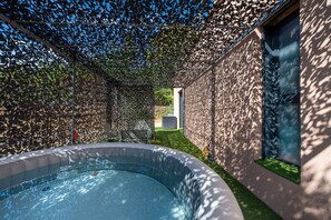 Ein Schwimmbecken mit einem einzigartigen, blattförmigen Dach darüber, umgeben von einem modernen Gebäude mit einer Steinaußenfassade.