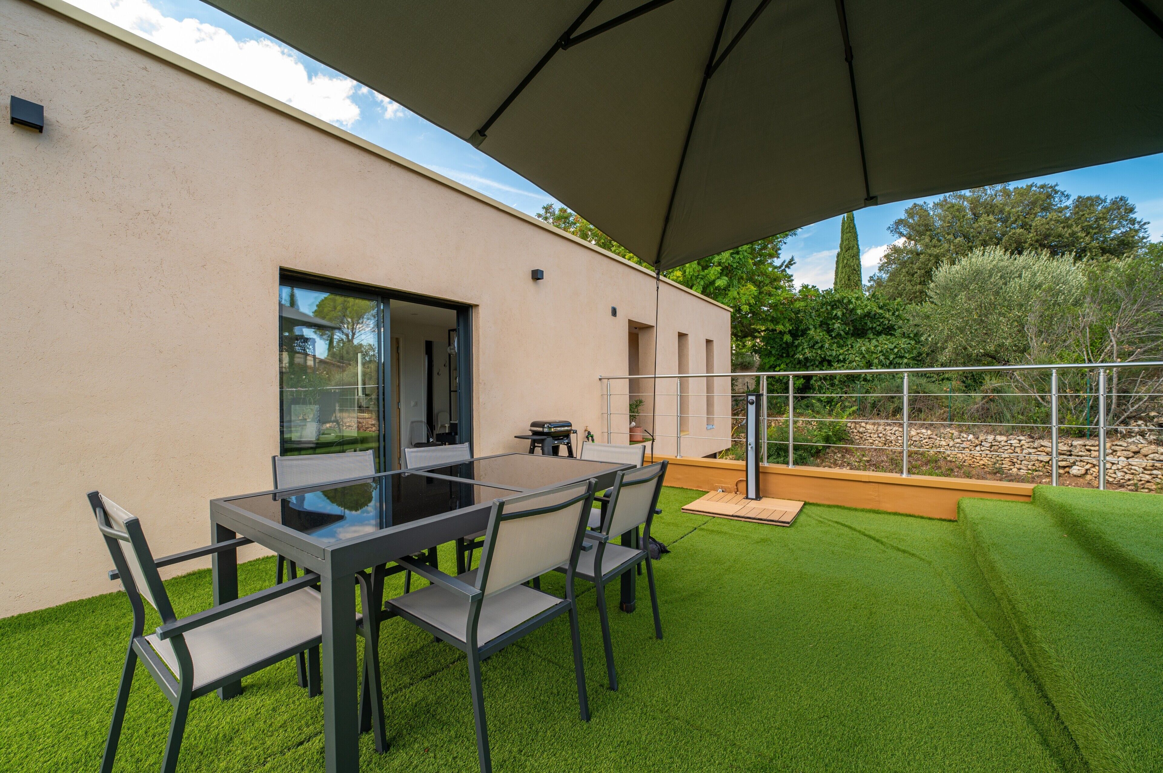 Une terrasse extérieure avec une table et des chaises, un espace abrité et une vue sur le paysage environnant.