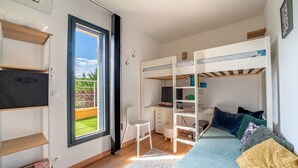 Een kleine slaapkamer met stapelbedden, een bureau, een stoel en een televisie.