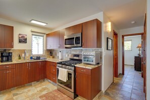 A modern kitchen with wooden cabinets, stainless steel appliances, and a tiled floor. - Private Oceanfront Escape on Moloka'i's East End (Kaunakakai)
