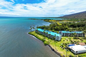 Ein Küstenhotel mit mehreren Gebäuden, einer Strandlage und üppiger Bepflanzung.