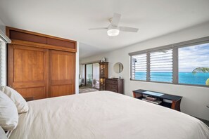 Ein Schlafzimmer mit Bett, Deckenventilator, Fenster mit Meerblick und Holzschrank.