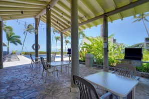 Eine Terrasse im Freien mit Tischen, Stühlen, einem Grill und Blick auf den Ozean.