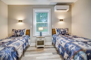 A bedroom with two beds, a window with blinds, a nightstand, and an air conditioning unit. - Family Fun! Indoor Jungle Gym, Hot Tub & Beach (Erie)