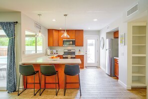 A modern kitchen with a central island, bar stools, a microwave, oven, and a refrigerator. - 'Twin Palms' Family Oasis in Glendale (Glendale)