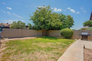 A backyard with a grassy lawn, a tree, a bush, and a barbecue grill. - 'Twin Palms' Family Oasis in Glendale (Glendale)