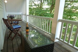 A wooden deck with a glass-top table, a bottle of champagne, and a chair with a cushion. - Apartment 4.3 – Holiday apartment in Graal-Müritz (Graal-Müritz)