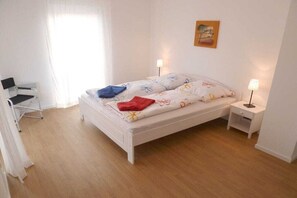 Un dormitorio con cama, mesitas de noche, una silla y un escritorio.