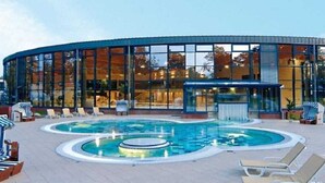 Um edifício moderno com área de piscina, incluindo espreguiçadeiras e uma banheira de hidromassagem.