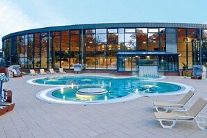 Un edificio moderno con zona de piscina, incluyendo sillas de descanso y un jacuzzi.