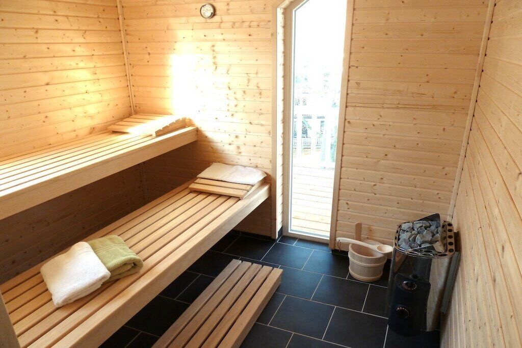 Un sauna avec des bancs en bois, une serviette, un seau et un appareil de chauffage pour sauna.