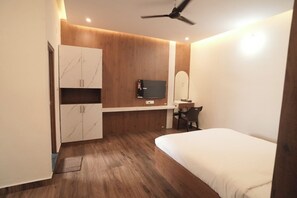 Une chambre à coucher avec un lit, un bureau, une chaise, une télévision et une armoire.