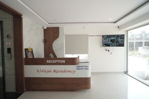Una recepción con diseño de madera, un horario de entrada y salida, y vistas al exterior a través de un ventanal amplio.