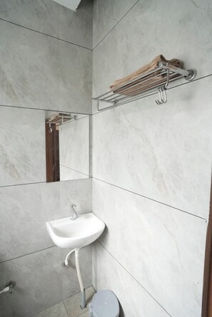 Une salle de bain avec un lavabo blanc, un porte-serviettes et des toilettes.