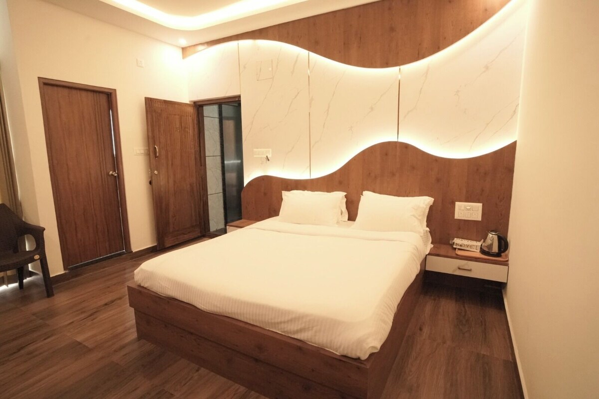 Une chambre avec un grand lit, une tête de lit en bois, une table de chevet avec une bouilloire et une armoire.