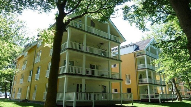 A multi-story building with balconies, surrounded by trees. - Holiday apartment with 1 bedroom (Graal-Müritz)