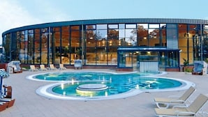 A modern building with a pool area, including lounge chairs and a hot tub. - Holiday apartment with 1 bedroom (Graal-Müritz)