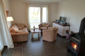 Una sala de estar con sofá, sillón, una mesita, televisor y chimenea.