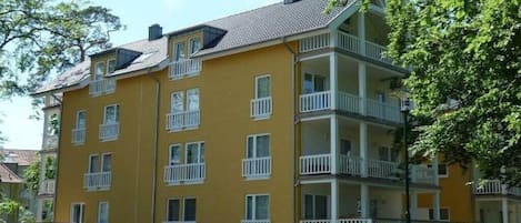 Un immeuble jaune à plusieurs étages, doté de balcons, qui semble être un complexe d’appartements résidentiels.