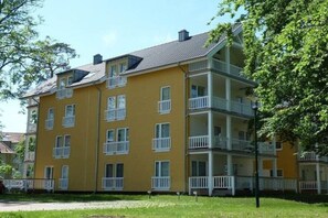 Ein mehrstöckiges, gelbes Gebäude mit Balkonen, vermutlich ein Wohnhaus.