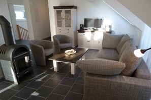 Una sala de estar moderna con sofá, sillones, una mesa de centro, chimenea y televisor.