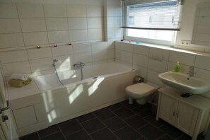 Un baño con bañera, inodoro y lavamanos.