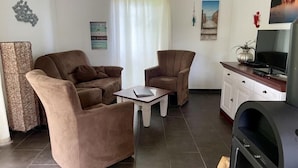 A living room with a sofa, two armchairs, a coffee table, a television, and a fireplace. - Holiday apartment with 1 bedroom (Graal-Müritz)