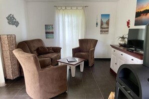 Una sala de estar con un sofá, dos sillones, una mesita de centro, un televisor y una chimenea.