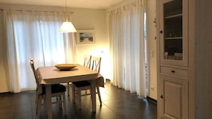 A dining area with a table, chairs, a hanging light fixture, and a cabinet. - Holiday apartment with 1 bedroom (Graal-Müritz)