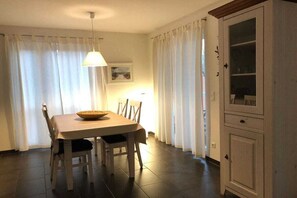 Un comedor con una mesa, sillas, una lámpara colgante y un armario.