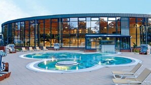 Um edifício moderno com área de piscina, incluindo espreguiçadeiras e uma banheira de hidromassagem.