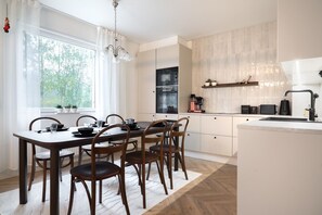 Eine moderne Küche mit Essbereich, ausgestattet mit einem großen Fenster, einer Chandelieber und einer Kaffeestation.