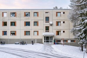 Ein mehrstöckiges Gebäude mit einer flachen Fassade, rechteckigen Fenstern und einem zentralen Eingang.