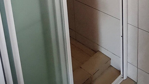 A corner of a room with a tiled floor and a glass door.