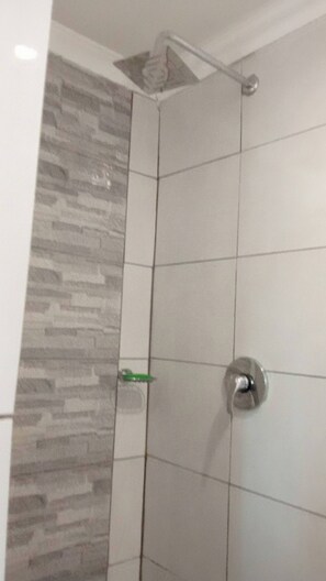 A bathroom with a shower area featuring a tiled wall and a corner showerhead. - Serene 3-bedroom House Rental Near Sun City Resort (Maile)