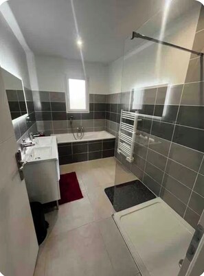 Een moderne badkamer met een bad, douche en wastafel.