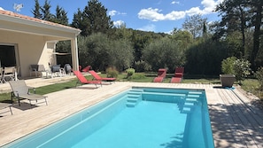 A swimming pool with red lounge chairs and a covered patio area. - Villa Les Oliviers (Lagorce)