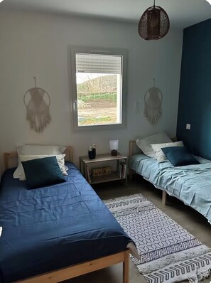 Een slaapkamer met twee bedden, een raam met uitzicht en een hanglamp.