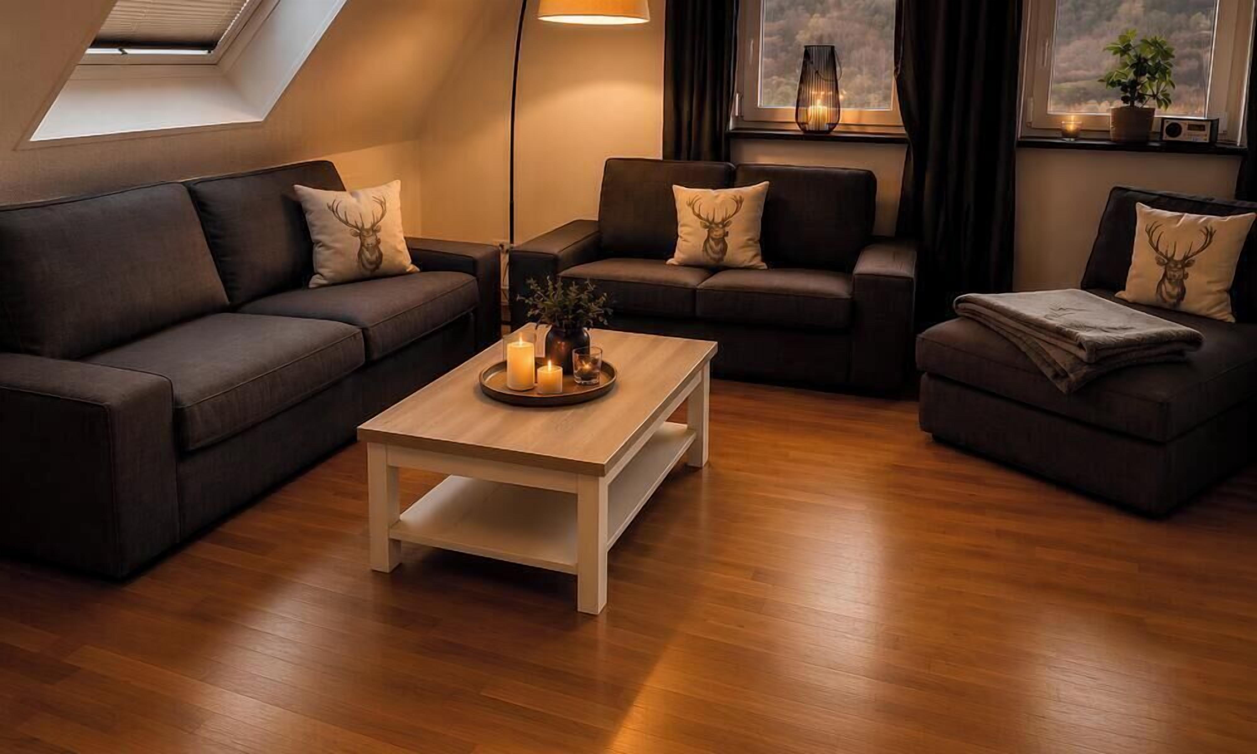 Una sala de estar moderna con piso de madera, dos sofás oscuros con almohadones decorativos, una mesa de centro y un tragaluz.