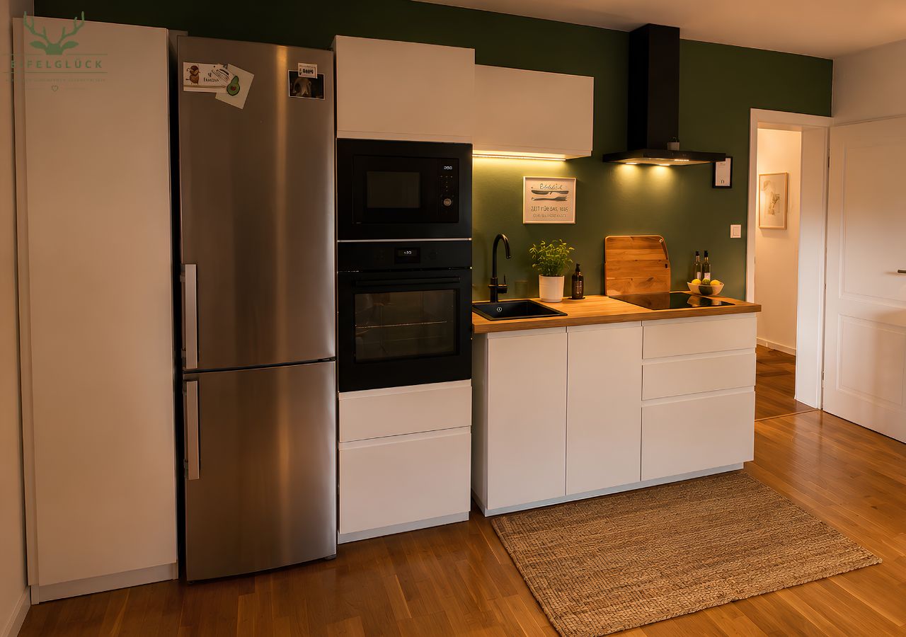 Una cocina compacta con refrigerador de acero inoxidable, horno empotrado y microondas.