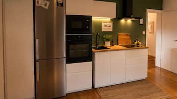Una cocina compacta con refrigerador de acero inoxidable, horno empotrado y microondas.