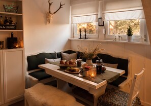 Un rincón acogedor con una mesa lista para tomar té, una cabeza de venado decorativa y una ventana con vista a árboles.