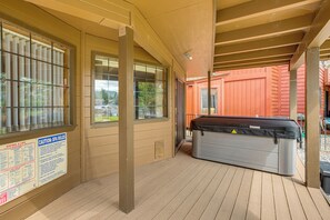A covered outdoor area with a hot tub, wooden deck, and a building with large windows. - Dock + Hot Tub! Waterfront Lake Tahoe Getaway (South Lake Tahoe)