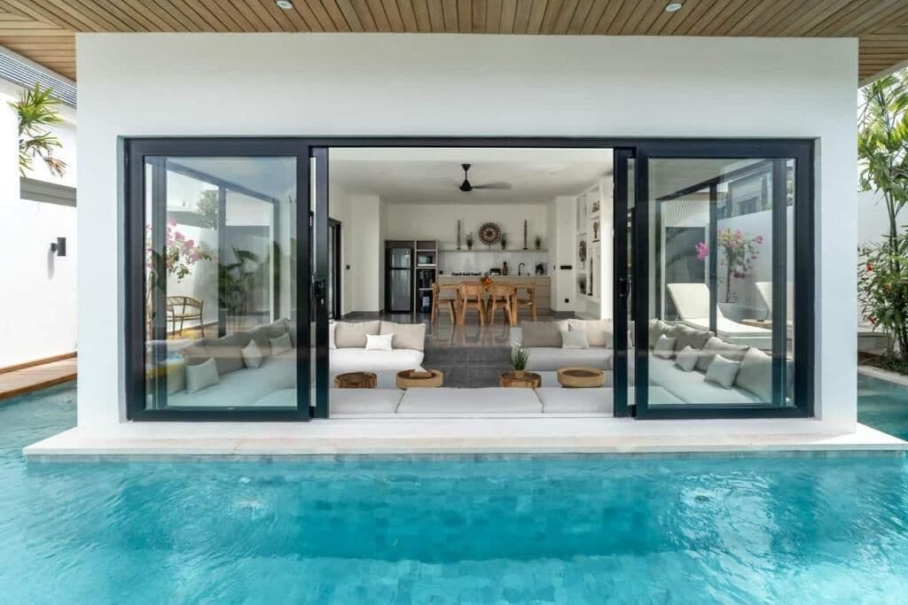 Een modern huis met een zwembad, een eetgedeelte en een woonkamer met banken en een salontafel.