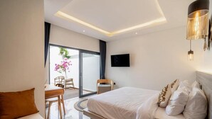 Een moderne hotelkamer met een bed, een zithoek, een televisie en een balkon met uitzicht.
