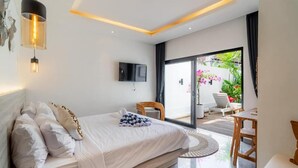 Een moderne slaapkamer met een bed, een televisie en uitzicht op een tuin door een schuifdeur.