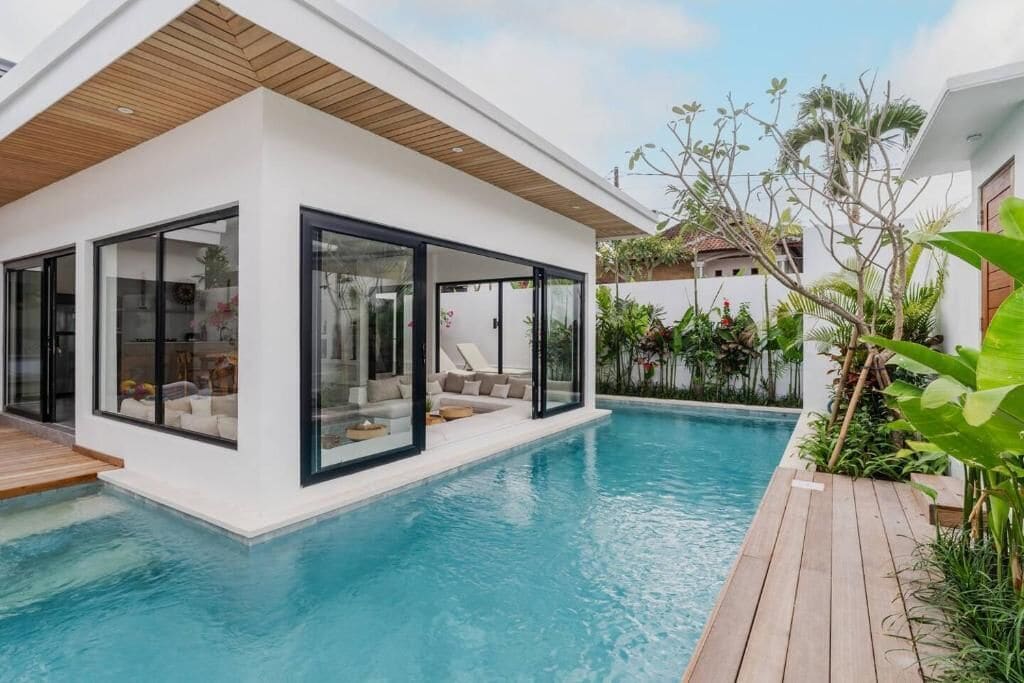 Une maison moderne dotée d’une piscine, de grandes baies vitrées et d’une terrasse en bois.