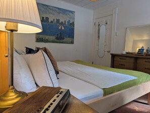 Una habitación de hotel con cama, lámpara, cuadro, espejo y cómoda de madera.