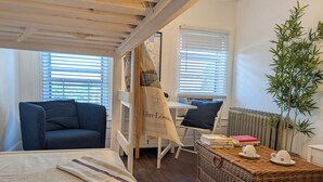 A cozy room with a bed, a chair, a table, and a radiator. - Vrbo Property (Staten Island)